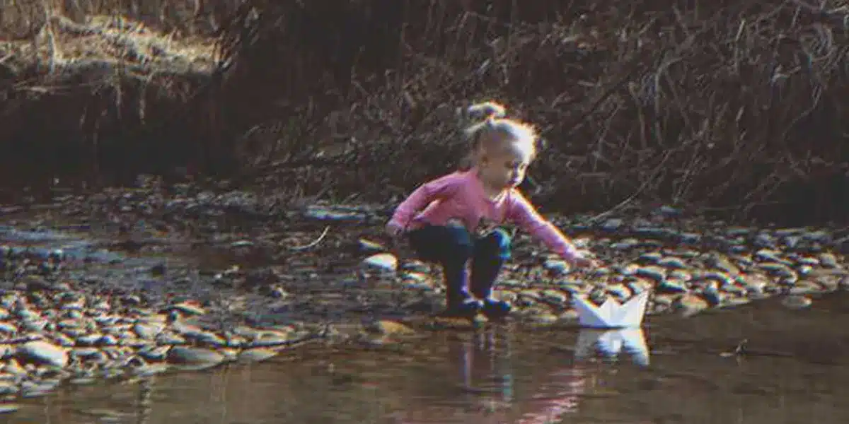Egy kislány talál a folyón egy papírhajót, amire az van ráírva: „Segíts nekünk”