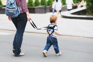 Az anya pórázt és hátizsákot rak a fiára, és elmagyarázza, miért csinálja ezt